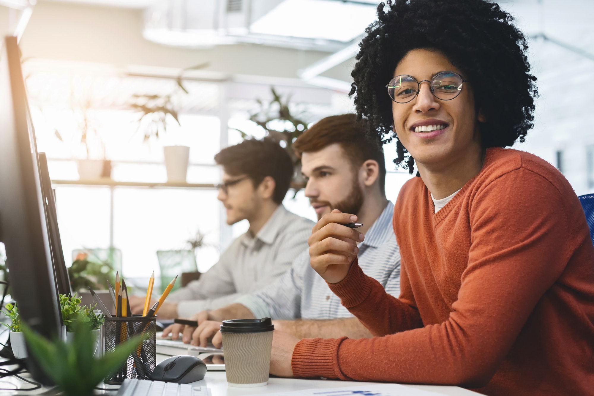 Cheerful african american guy smiling at camera at coworking